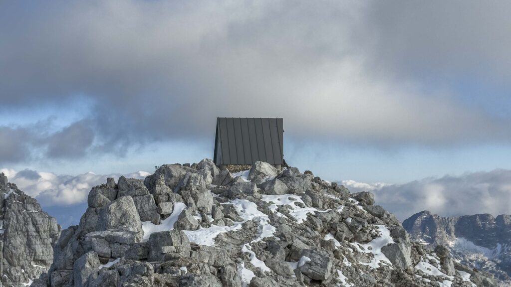 Rifugio in montagna su un picco roccioso innevato.