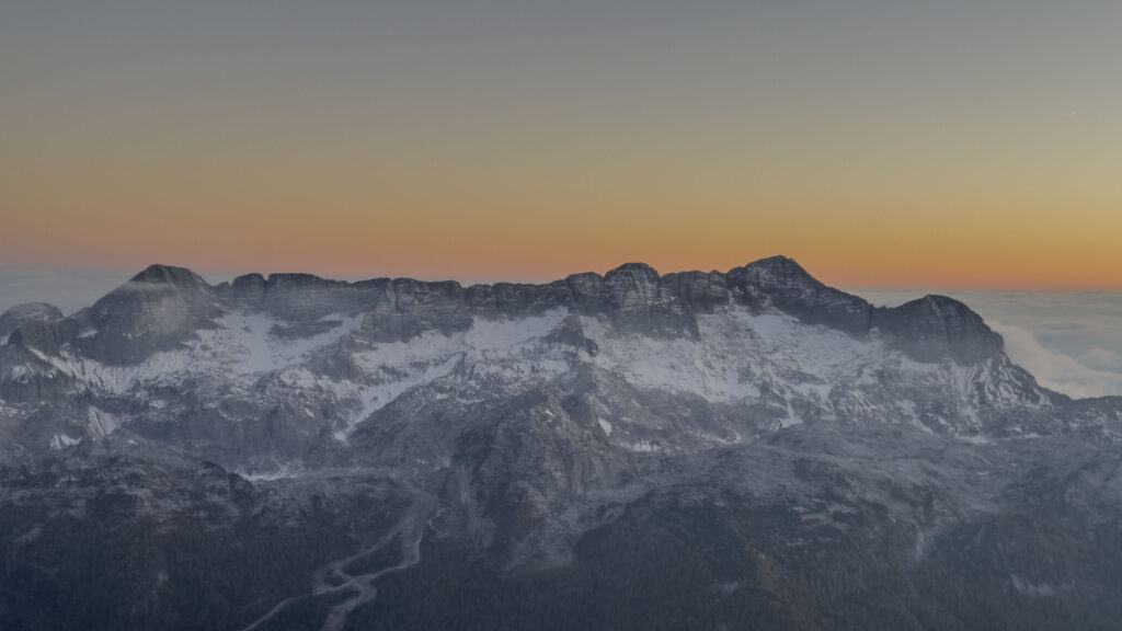Montagne innevate al tramonto con cielo arancione
